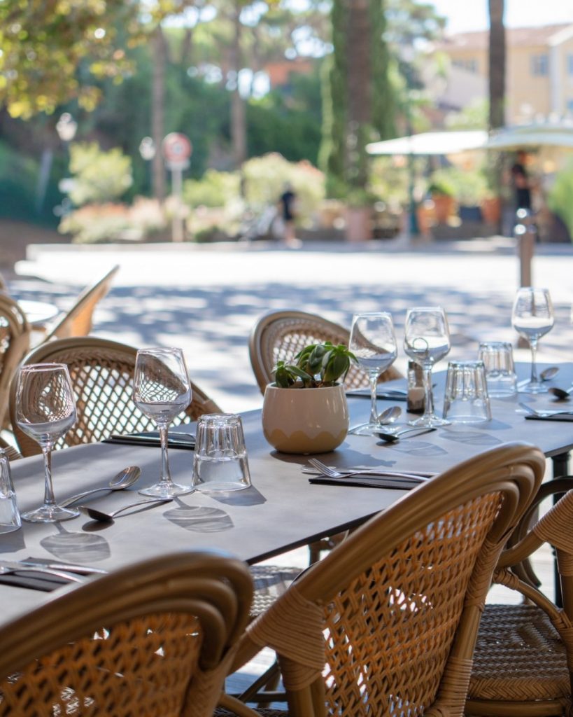 Table dressée en terrasse au Restaurant Le Progrès, vaisselle élégante et ambiance historique à Bormes-les-Mimosas.