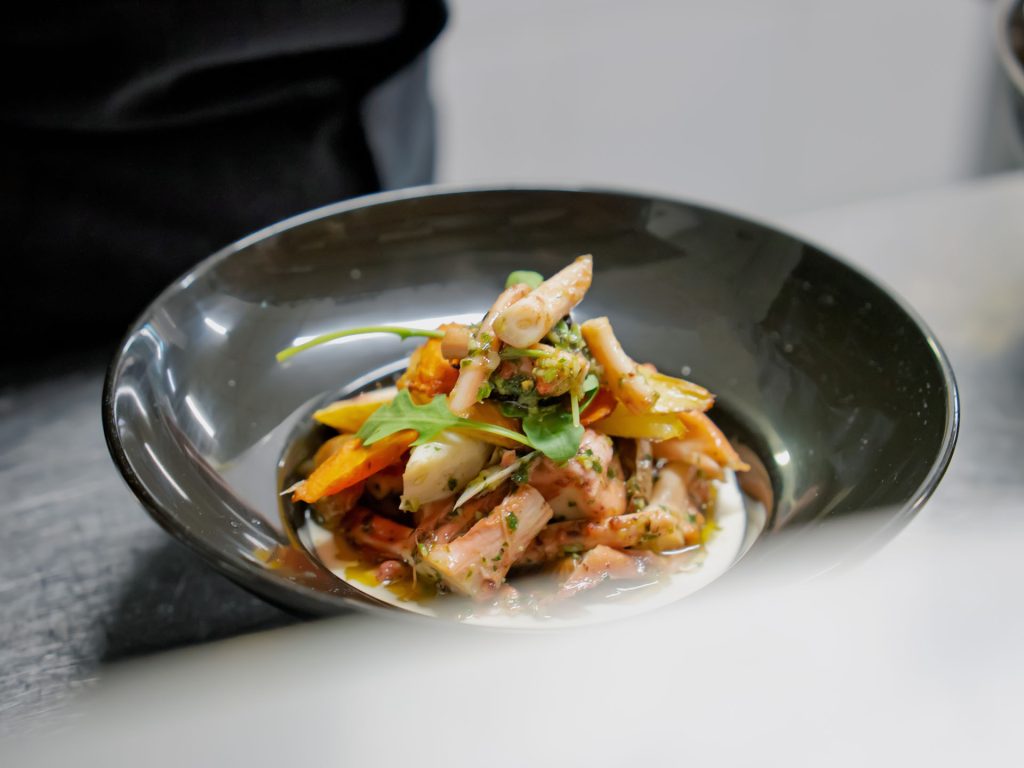 Des penne, du poulet et des légumes frais, accompagnés d’une salade verte servie dans un bol raffiné et parsemée d’herbes aromatiques.