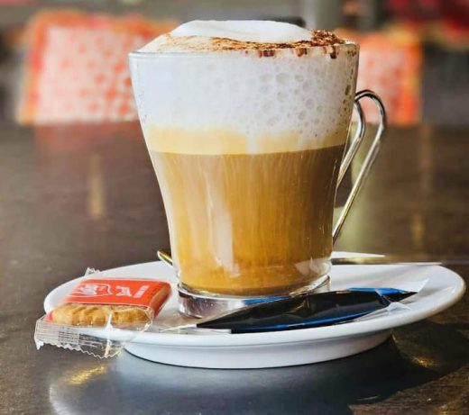 Cappuccino sur soucoupe, biscuit et cuillère au Restaurant Le Progrès, Bormes-les-Mimosas, depuis 1909.