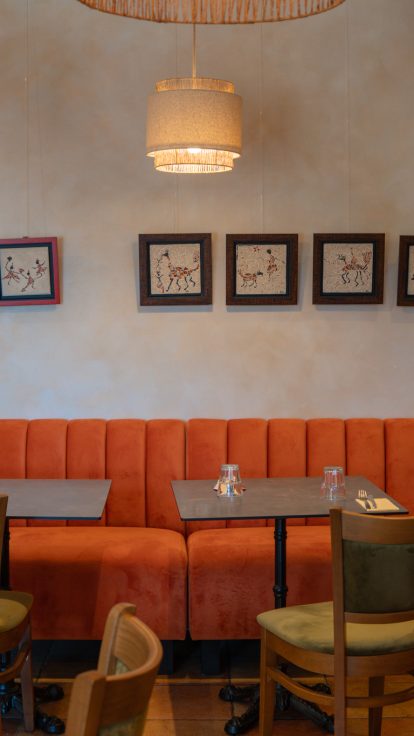 Intérieur chaleureux du Restaurant Le Progrès, banquettes orange, bois, plantes, héritage depuis 1909.