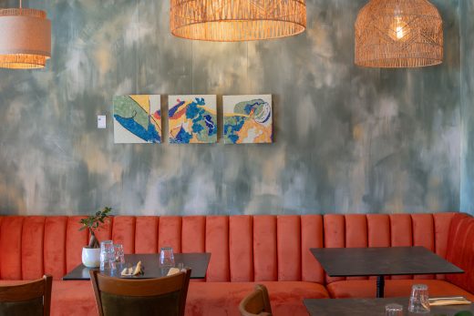 Élégant bistrot, banquettes orange et tables dressées, ambiance chaleureuse au cœur de Bormes-les-Mimosas.
